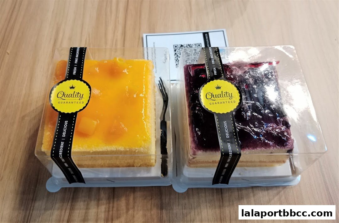 Two slices of cake, one mango and one blueberry, packaged for takeaway.
