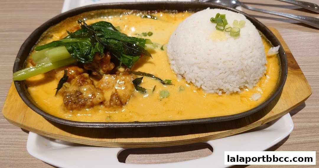 A sizzling hot plate dish with rice, vegetables, and a creamy sauce.