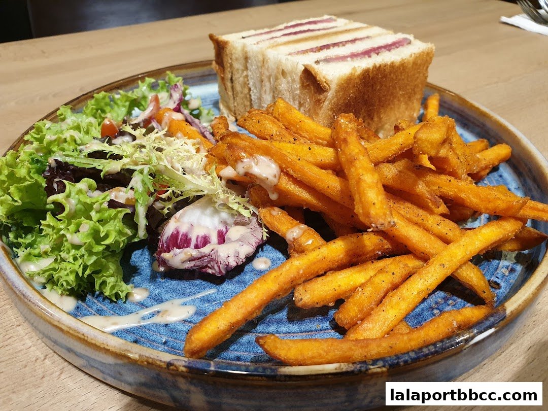 A plate of steak sandwich with fries and salad, seasoned with pepper and salt.