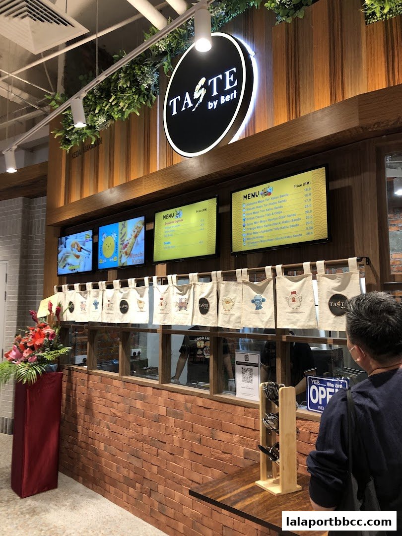A food stall with menus displayed on screens and a selection of bagged items hanging.