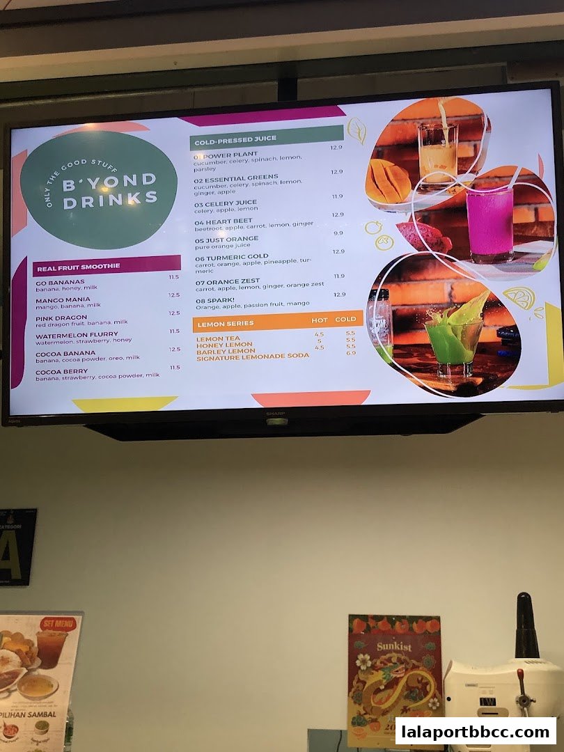 A digital menu board displaying various cold-pressed juices, real fruit smoothies, and lemon series drinks.