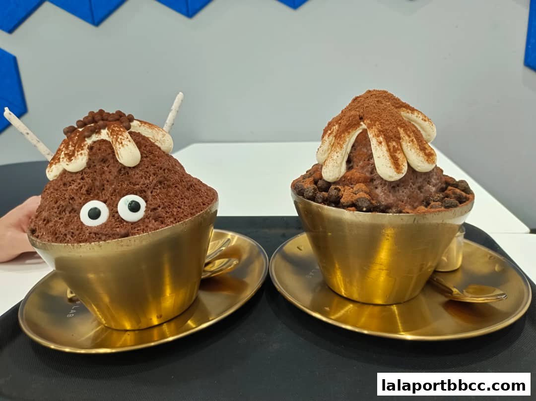 Two chocolate shaved ice desserts with whipped cream and toppings served in golden bowls.