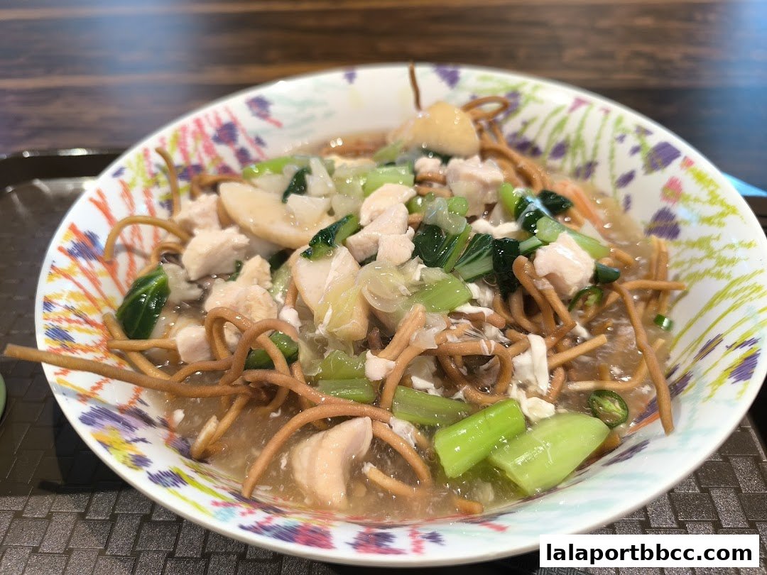 A close-up of a delicious noodle dish with chicken and vegetables in a decorative bowl.