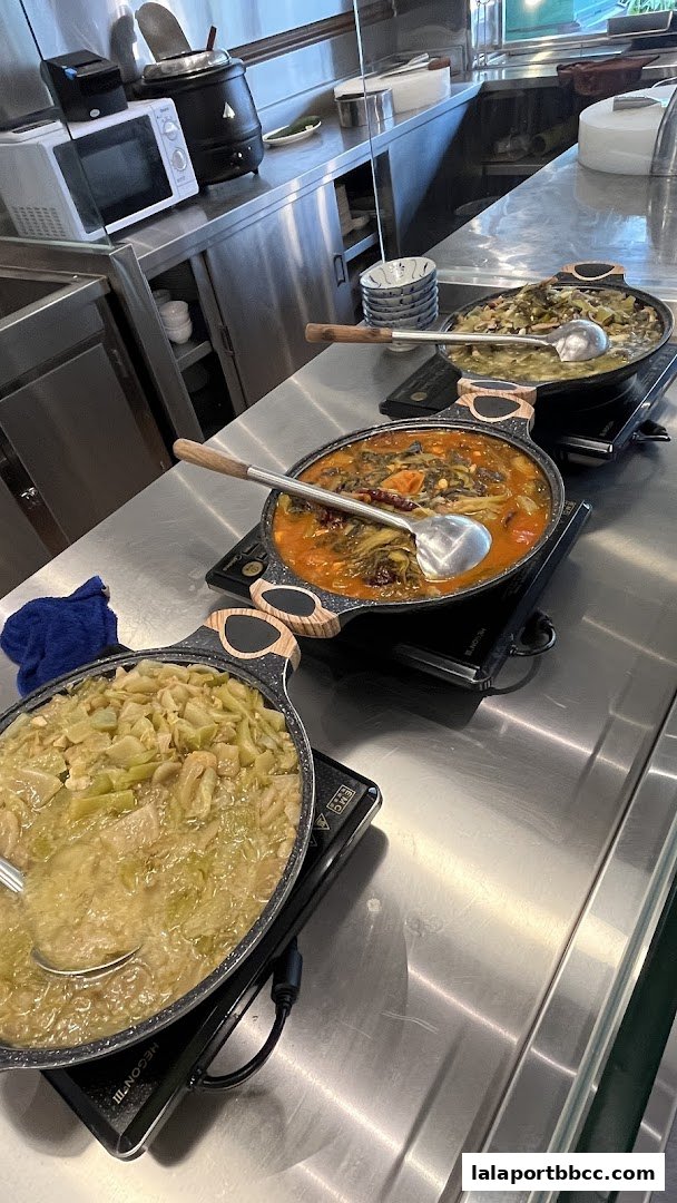 Three large pots of savory porridge are displayed on a stainless steel counter.