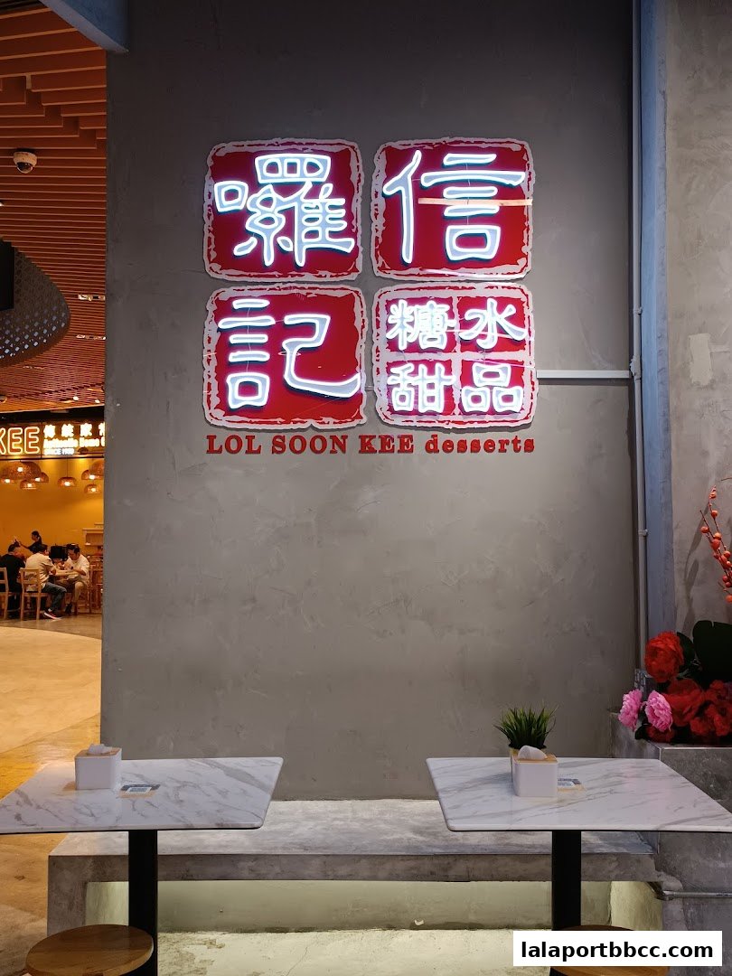 Neon sign for Lol Soon Kee Desserts with seating area in front.