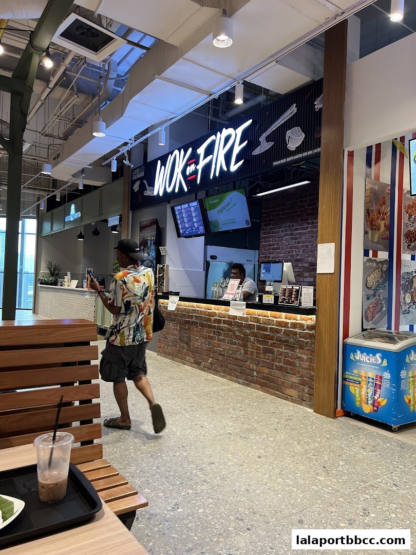 A person walks past the Wok On Fire restaurant counter with a menu displayed on screens.