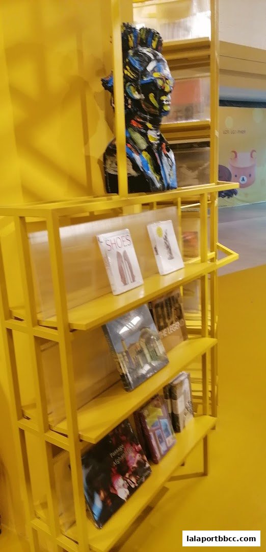 A yellow shelf displays books and a colorful bust sculpture.
