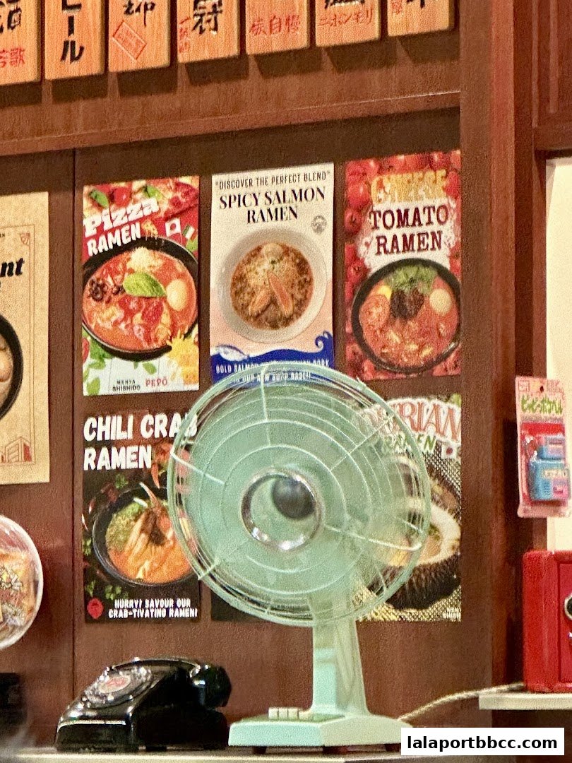 A wall display featuring ramen advertisements, a vintage fan, and a rotary phone.