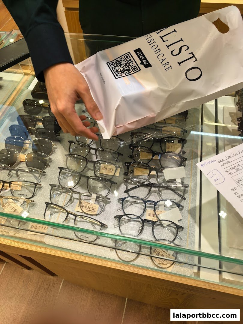 A person holds a CALISTO VISIONCARE bag over a display of eyeglasses.