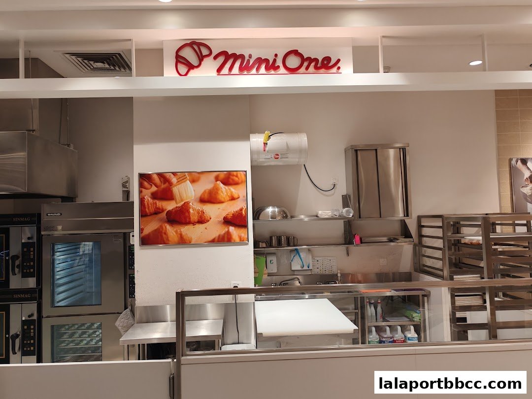 The interior of a bakery with ovens, a counter, and a picture of croissants.