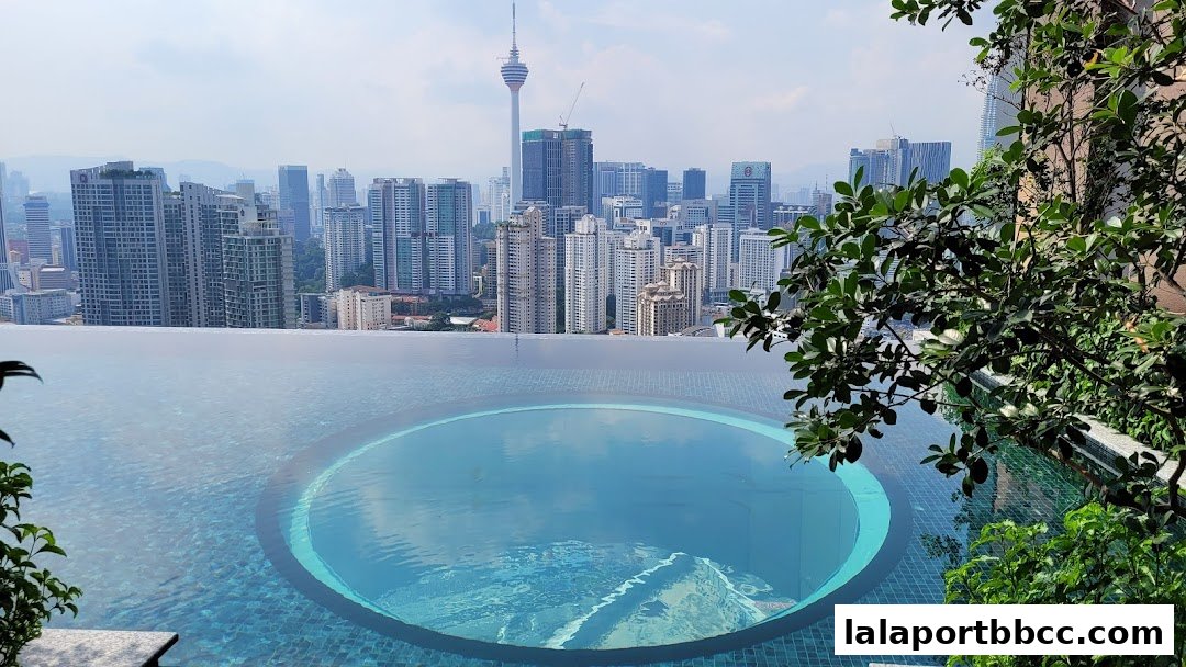 An infinity pool with a city skyline view, featuring lush greenery.