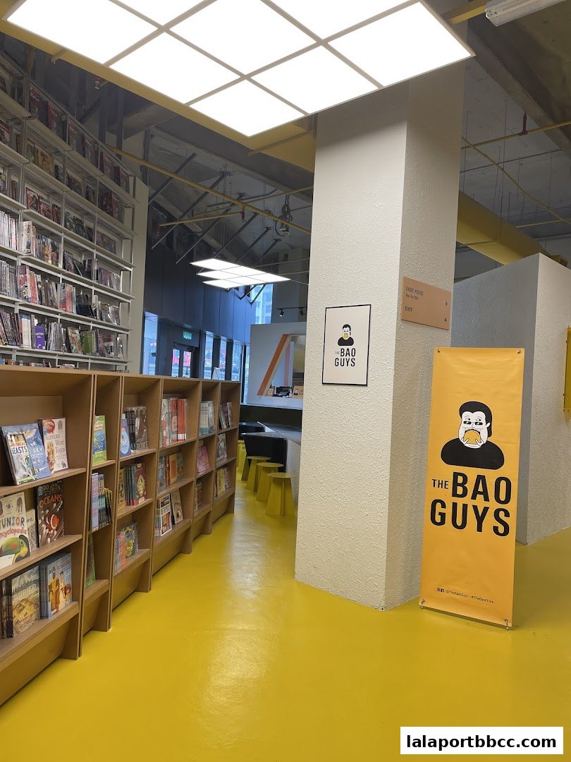 A bright yellow floor leads to a shop with books on shelves and a prominent banner for 'The Bao Guys'.