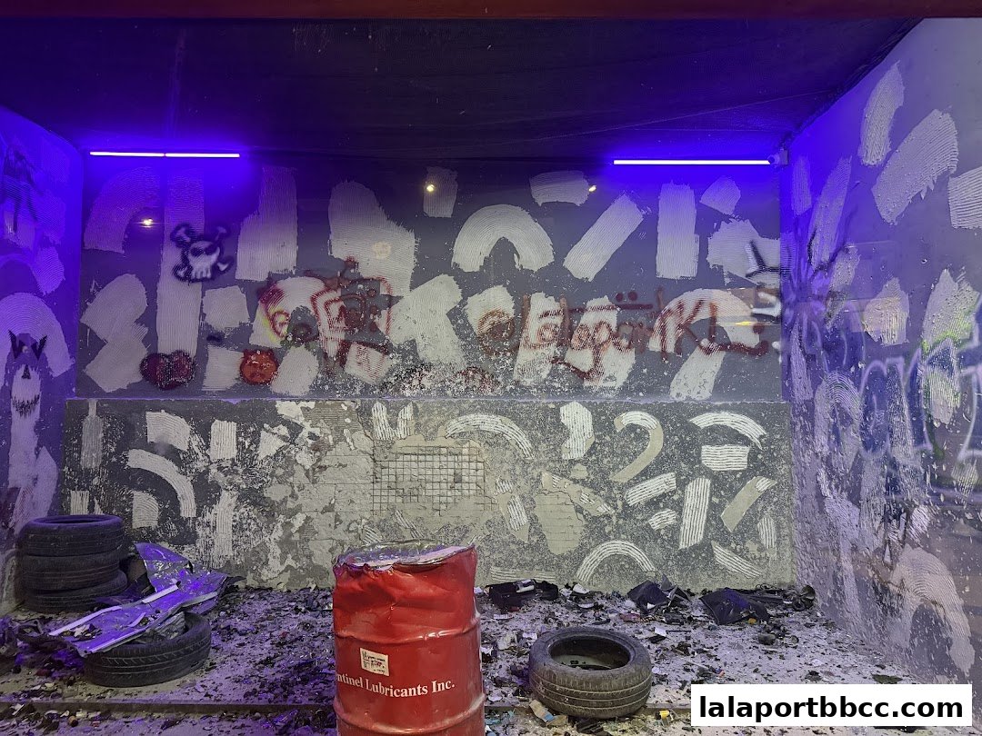 A gritty, urban-themed display with graffiti, tires, and a red barrel under blue lights.