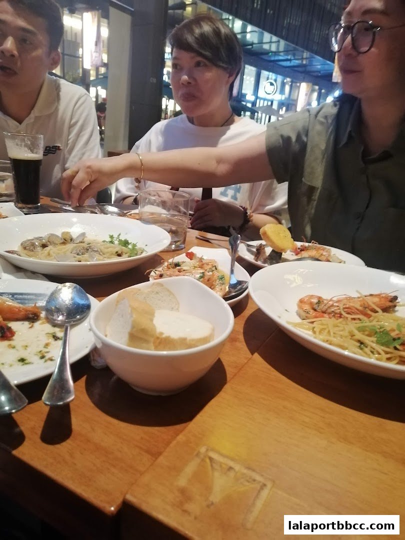 People enjoying a meal with pasta, bread, and drinks at a restaurant.