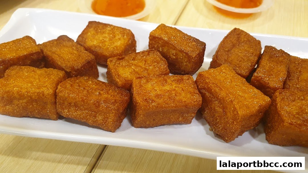 A plate of golden-brown fried tofu cubes served with dipping sauce.