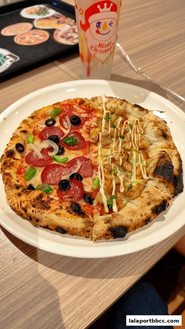 A delicious half-and-half pizza with pepperoni and chicken toppings, served on a white plate with a drink.