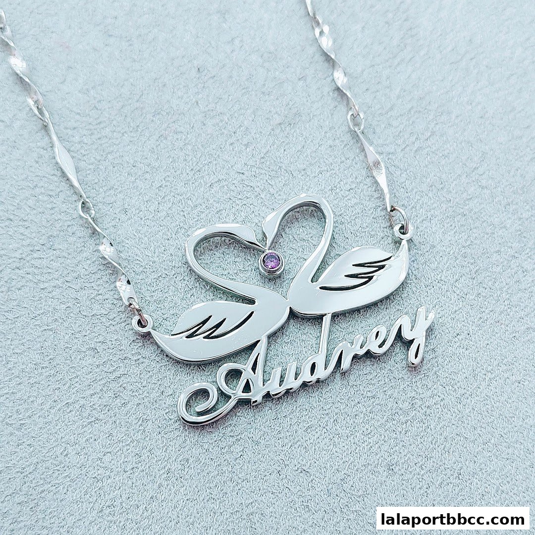 A silver necklace with a swan design and the name 'Audrey' in cursive.