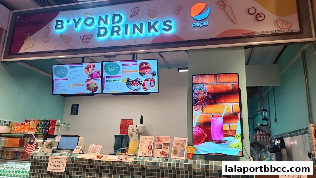 A brightly lit beverage shop counter with digital menus and a vibrant display.