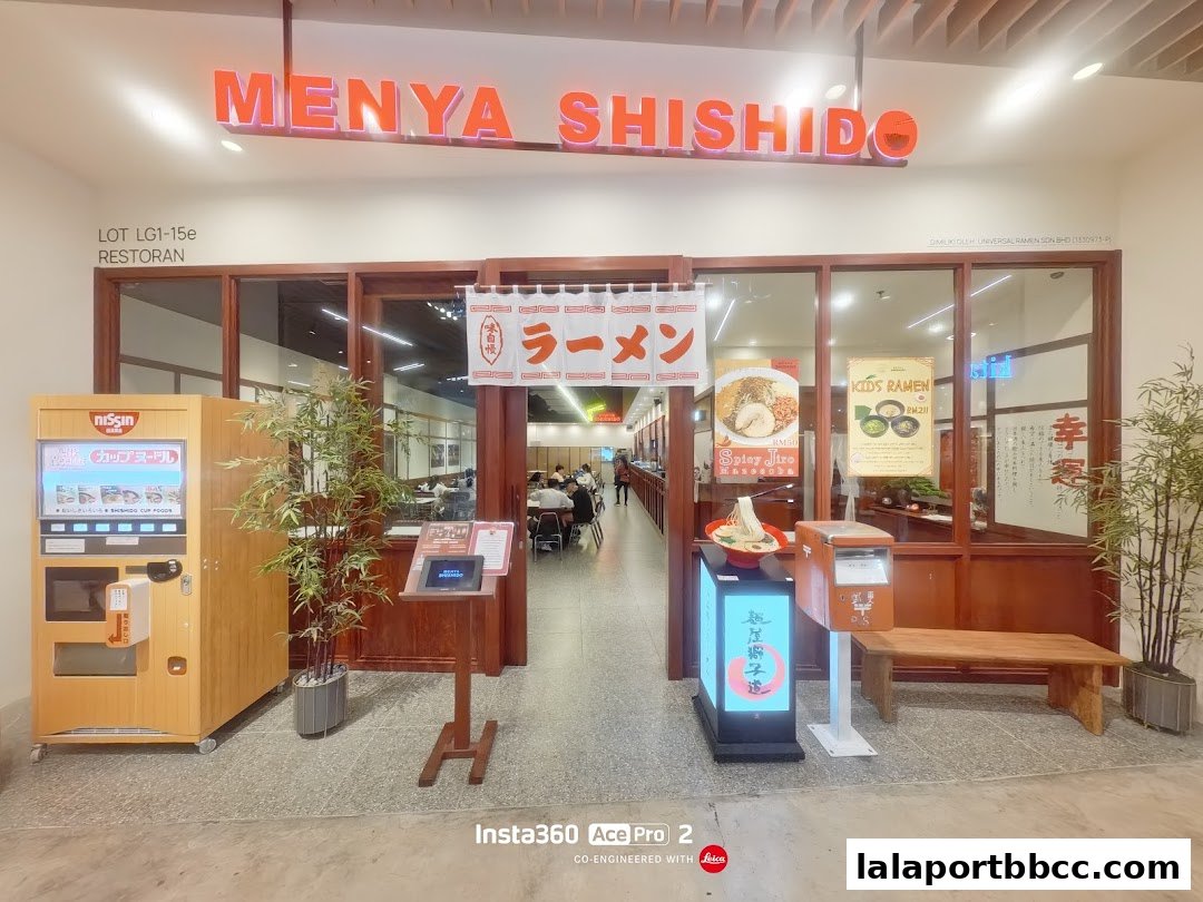 The entrance of Menya Shishido, a ramen restaurant, with a vending machine and seating area.