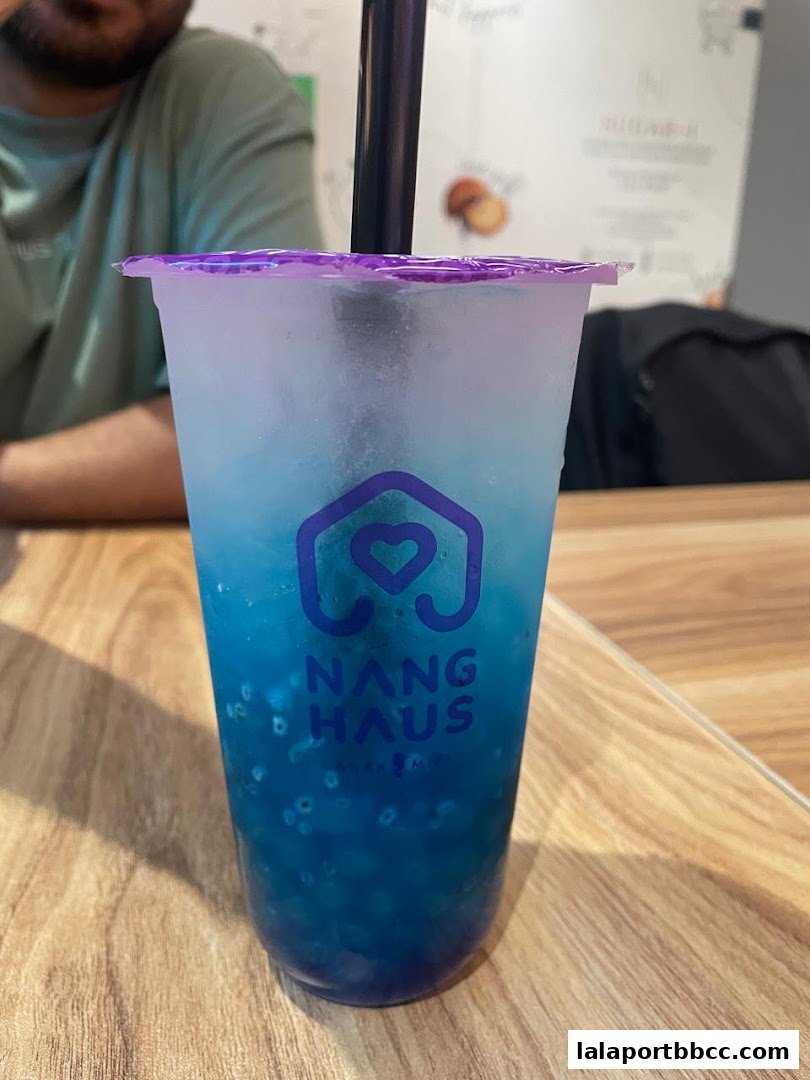 A close-up of a blue beverage with tapioca pearls and the Nang Haus logo.