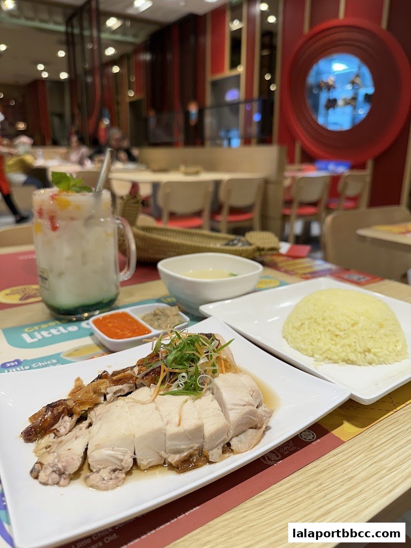 A plate of delicious chicken rice with a refreshing drink and dipping sauces.