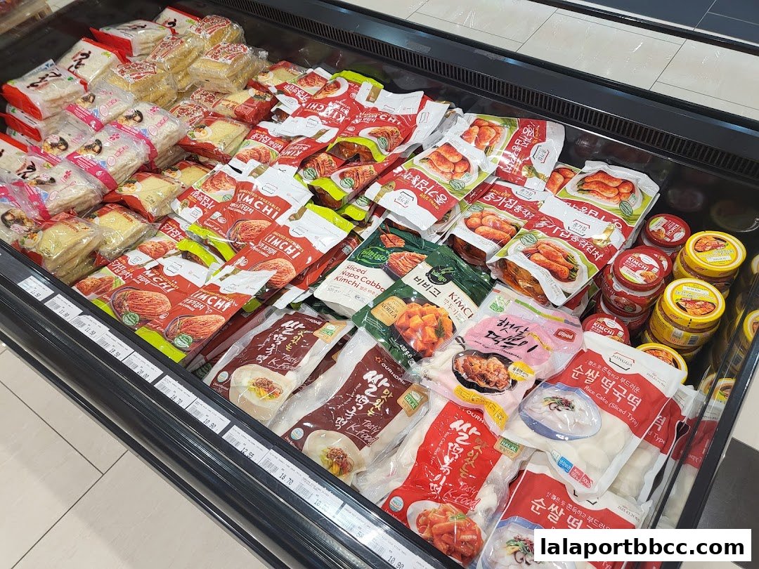 A refrigerated display case filled with various Korean food products, including kimchi and rice cakes.