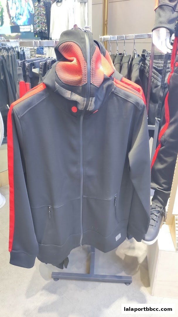 A black hooded jacket with red accents displayed on a rack in a clothing store.