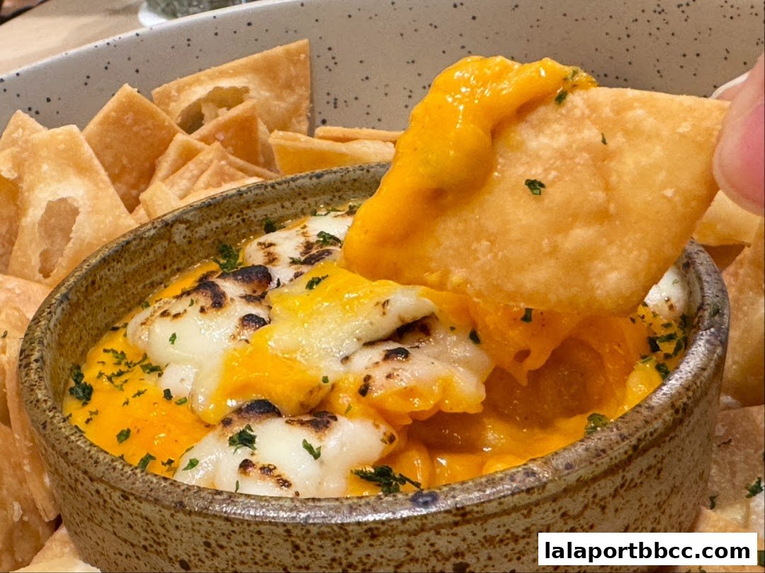 A close-up shot of a cheesy dip with tortilla chips, garnished with parsley.