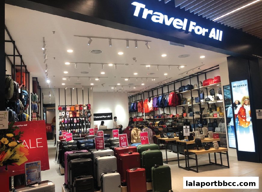 Interior view of a travel goods store showcasing luggage, bags, and apparel with sale signs.