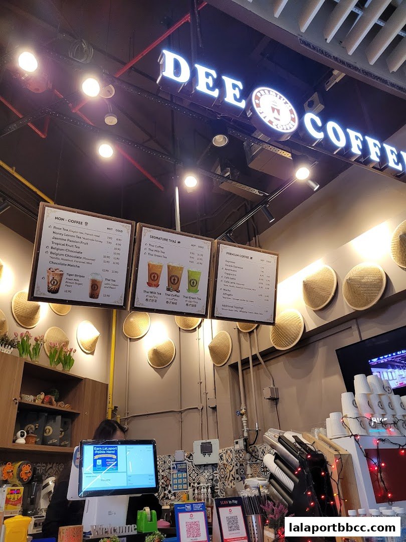 A coffee shop counter with menus displaying drinks and prices, and a cashier station.