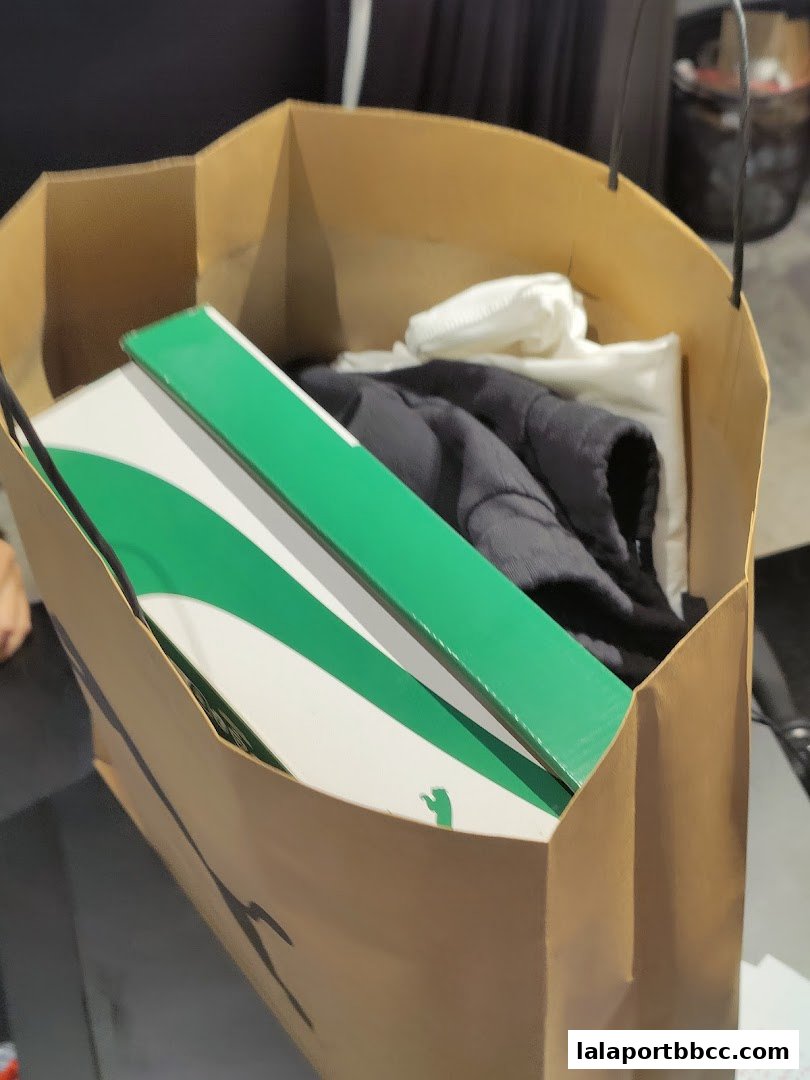 A shopping bag filled with PUMA branded items, including a shoe box and clothing.