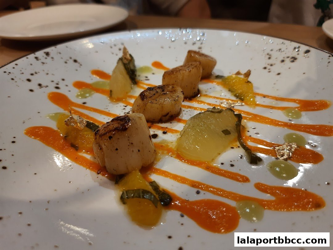 A beautifully plated dish of seared scallops with vibrant sauces and garnishes.