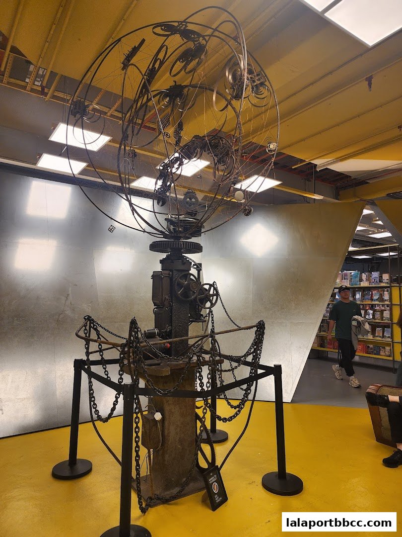 A large, intricate metal sculpture with chains in the center of a brightly lit space.