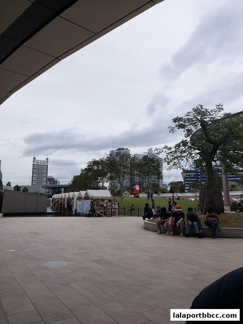People relaxing in an outdoor plaza with market stalls and festive decorations.