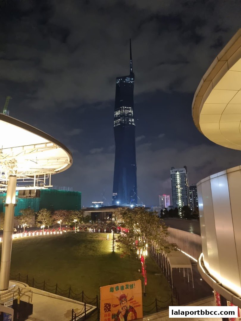 A nighttime view of a city skyline with a tall skyscraper and illuminated buildings.