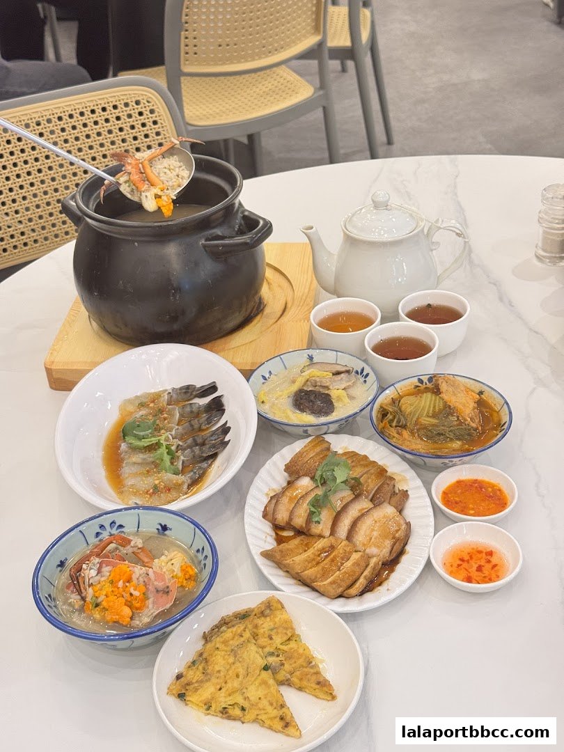 A spread of Teochew porridge dishes including seafood, meat, and omelets, served with tea.