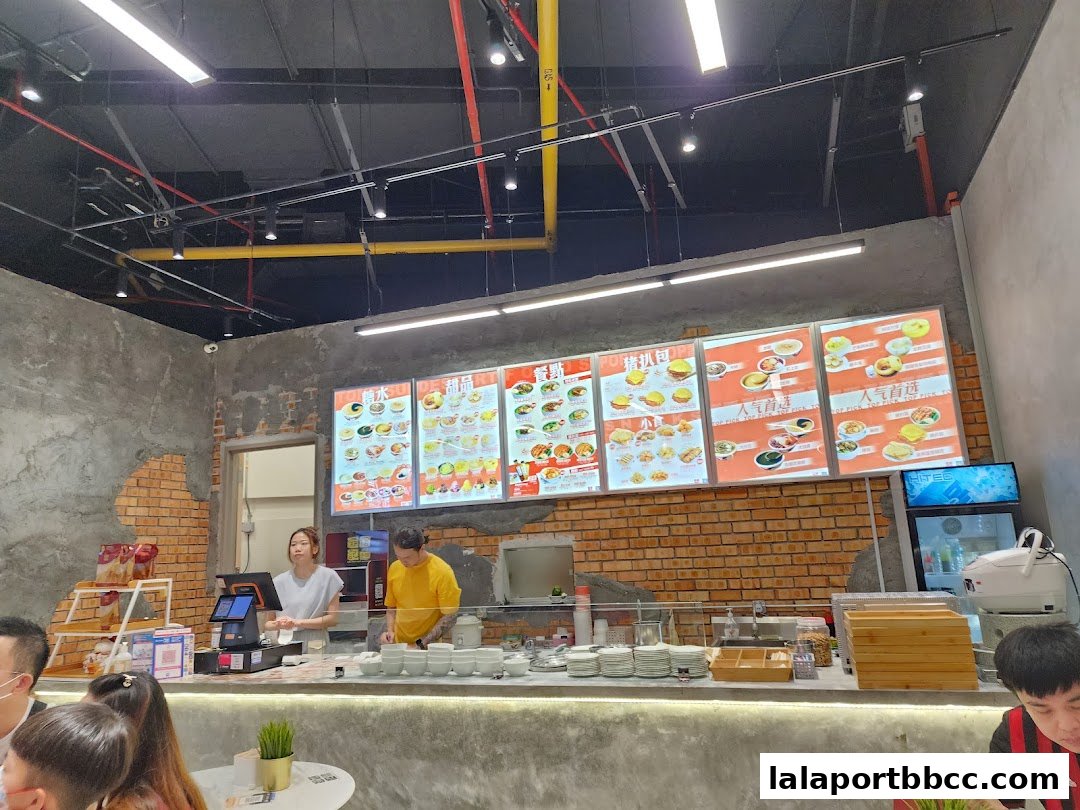 A dessert shop counter with illuminated menus displaying various sweet treats and staff serving customers.