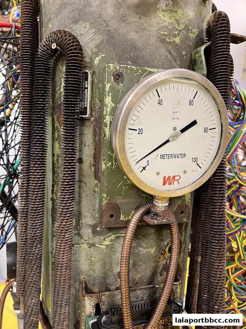 Close-up of a vintage industrial gauge with wires and pipes attached.