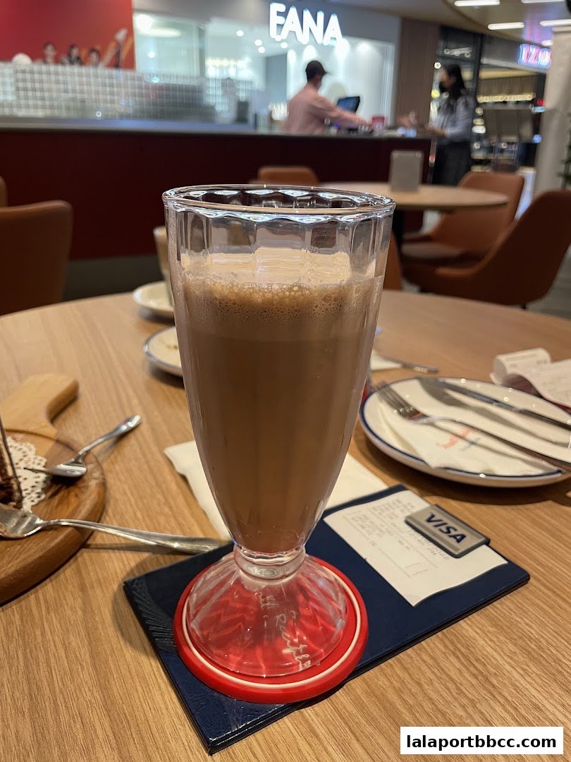 A close-up of a chocolate drink on a table with a receipt and cutlery.