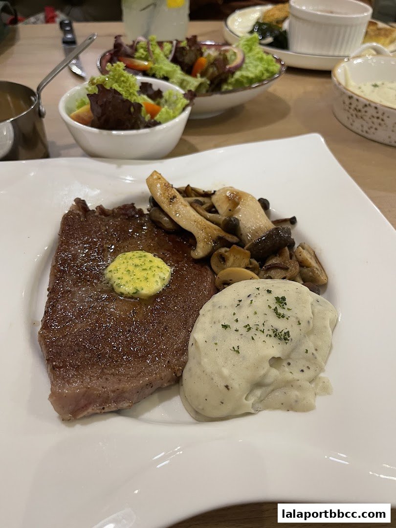 A perfectly cooked steak with mashed potatoes, mushrooms, and a side salad.