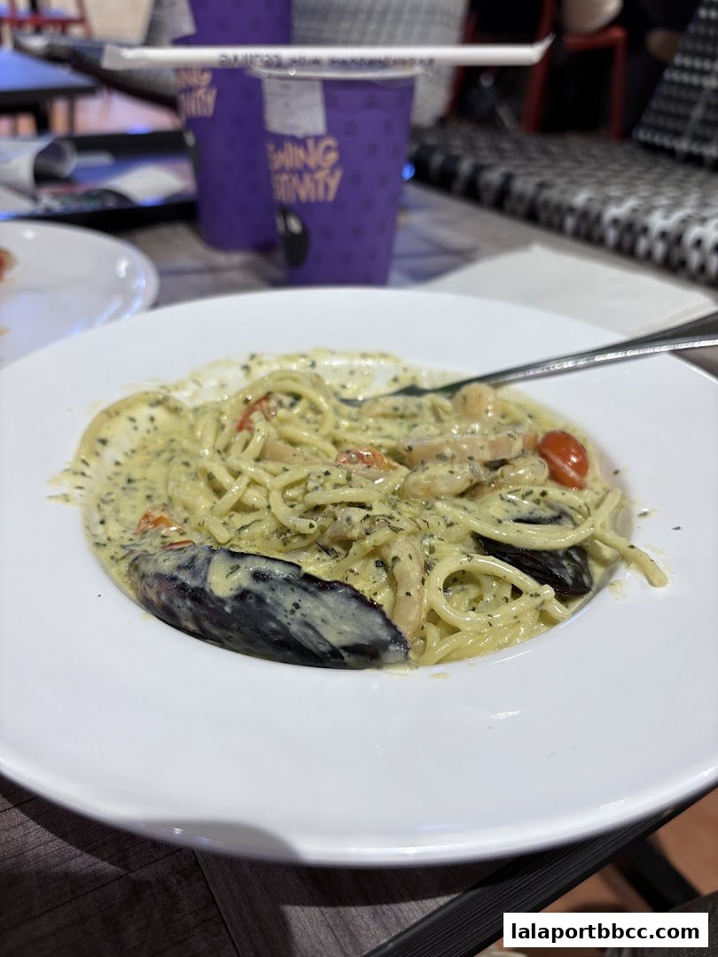 A close-up of a creamy seafood pasta dish with mussels and cherry tomatoes.