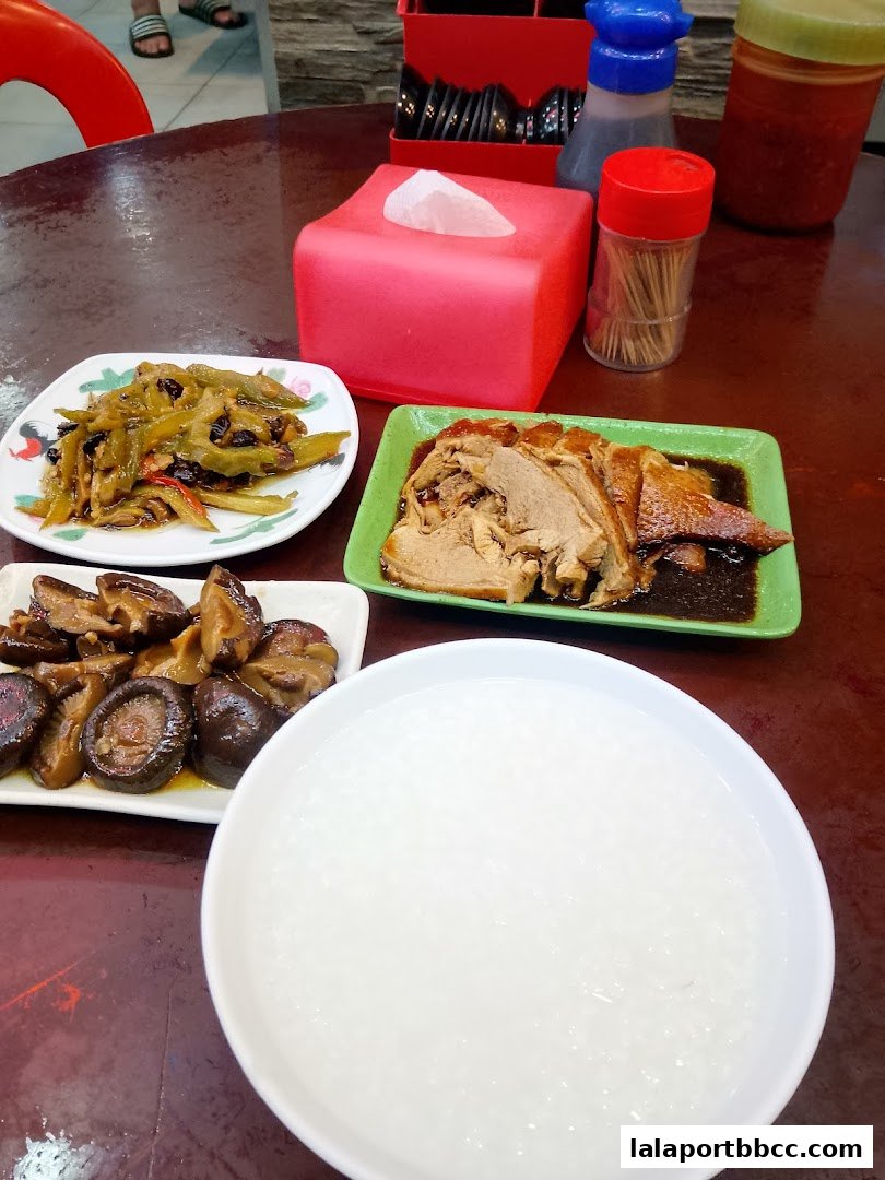 A table laden with Teochew porridge, braised duck, mushrooms, and bitter gourd.