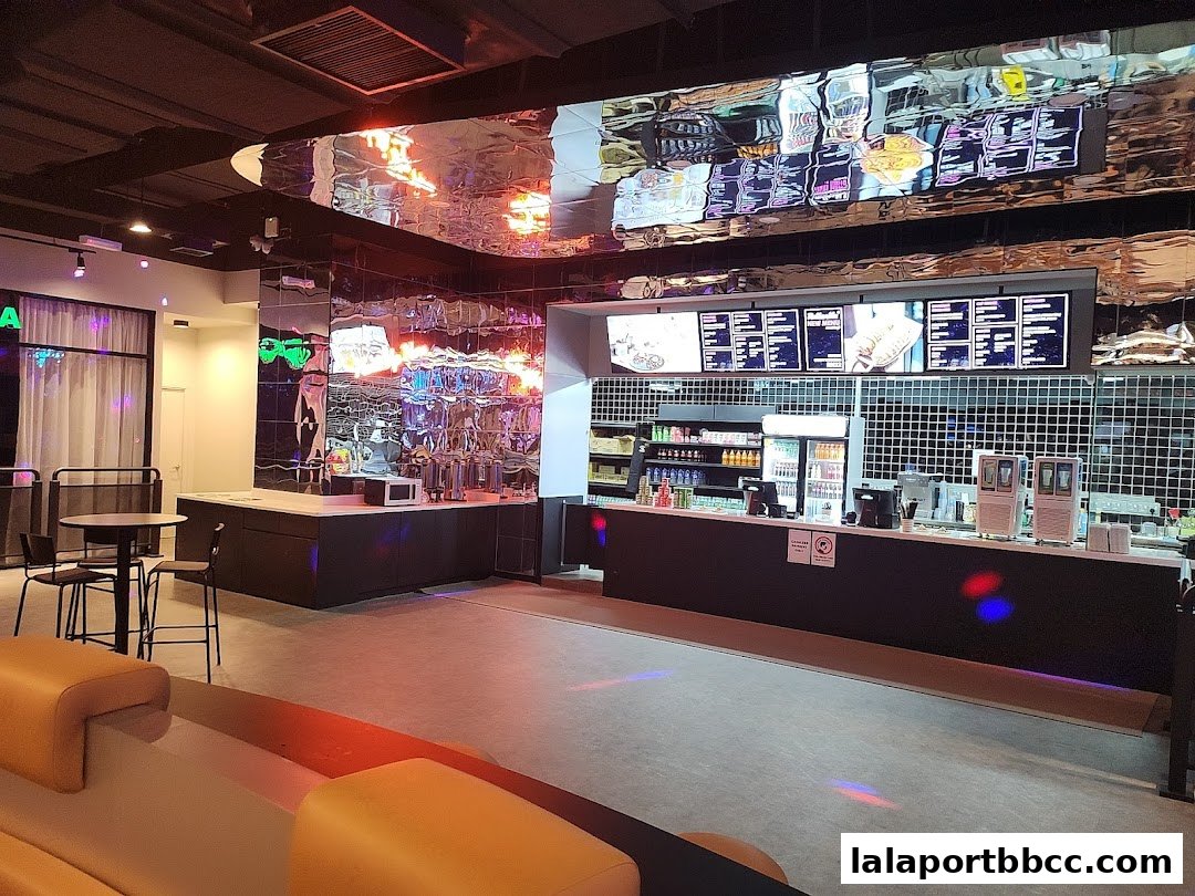 Interior view of a modern food service counter with digital menus and seating.