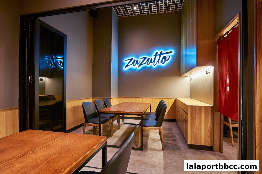 Interior of a modern restaurant with wooden tables, chairs, and a neon sign.