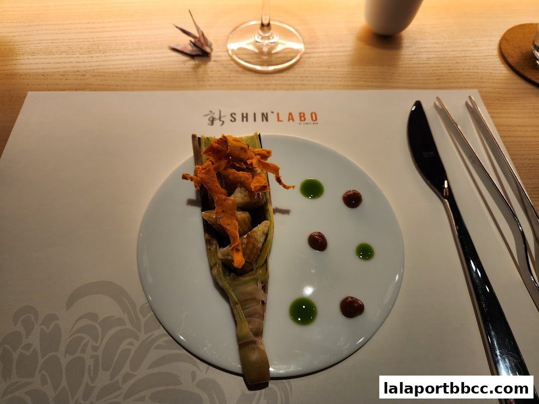 A beautifully plated dish with crispy toppings and sauces on a white plate at ShinLabo.