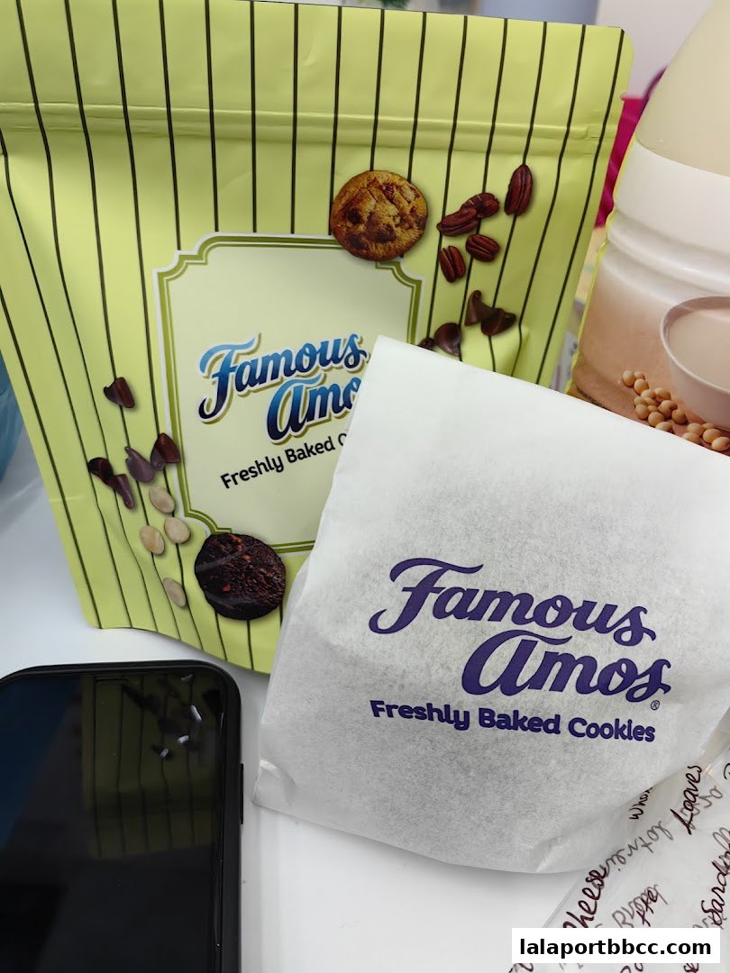 Famous Amos cookies in packaging with a phone and other items.