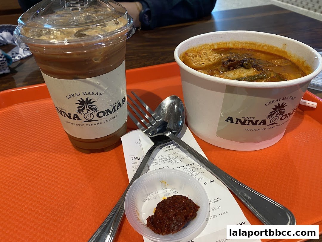 A tray with a drink, a bowl of curry, cutlery, and a receipt from Auntie Anna Pak Cik Omar.