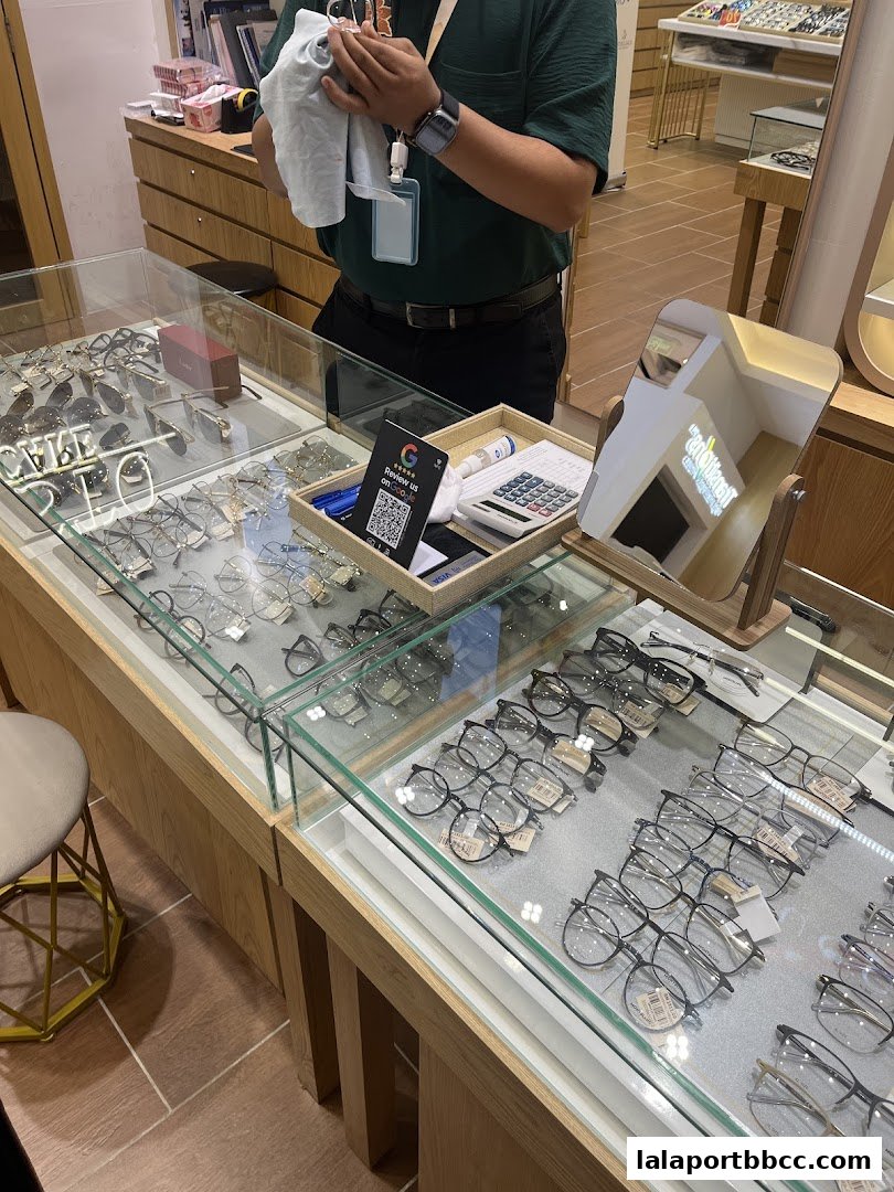 A display case filled with various eyeglasses, with a staff member cleaning glasses.