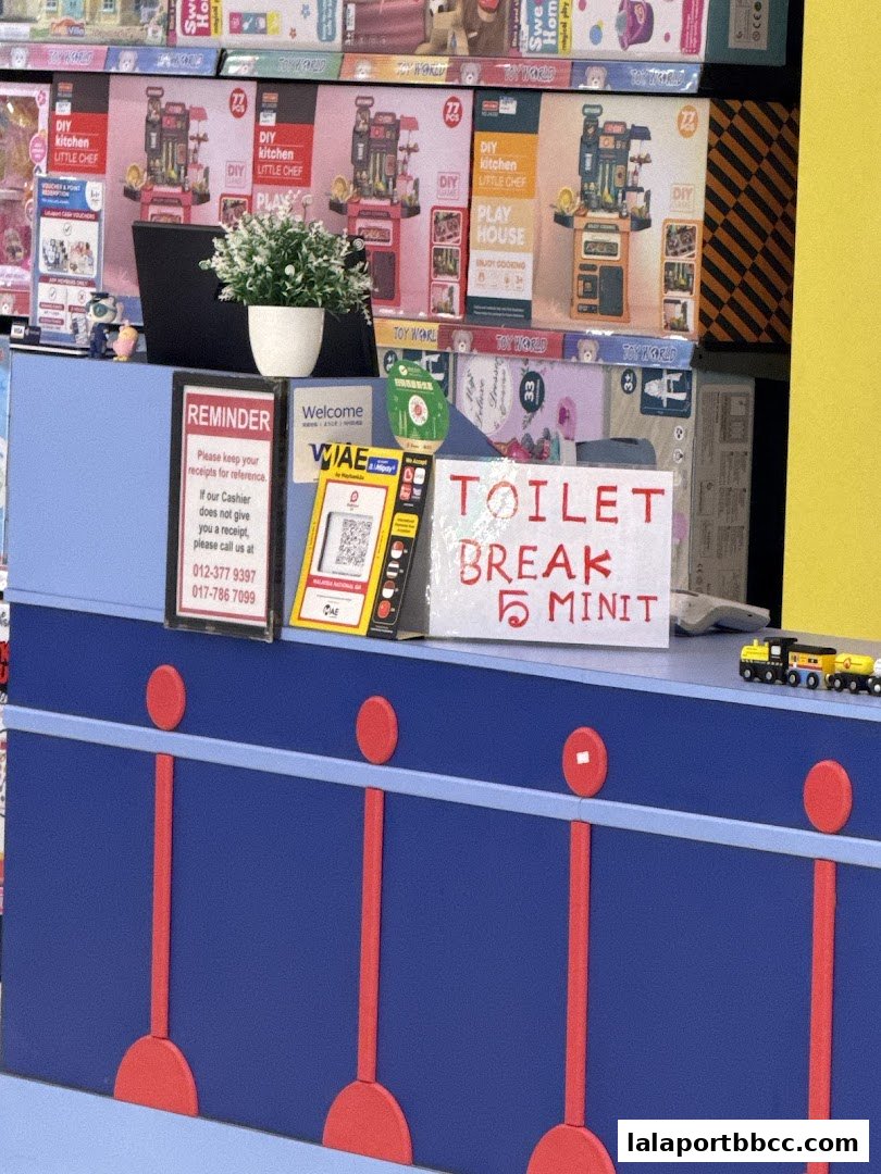 A counter at Toy World LaLaport BBCC with various toys and a 'Toilet Break' sign.