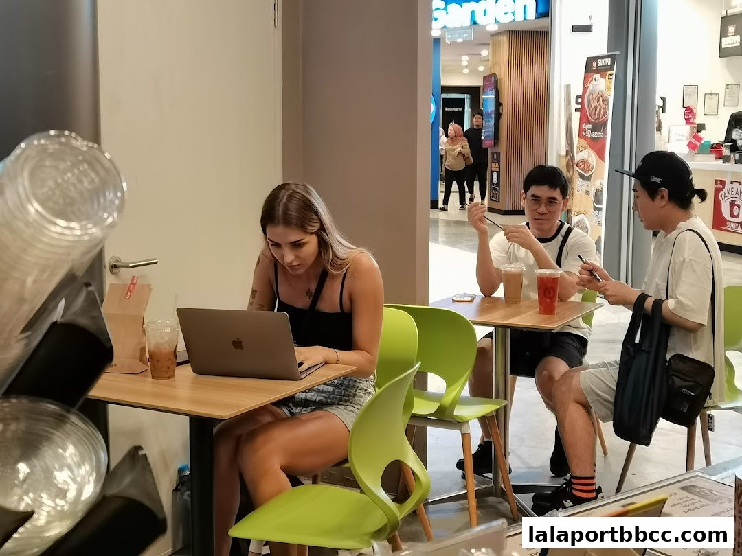 People enjoying coffee and working on laptops inside a modern cafe.